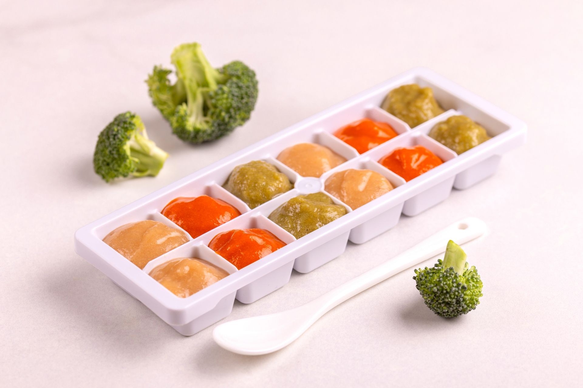 Daycare overnight care food in ice cube trays ready for freezing with ingredients on clean white background. Copy space